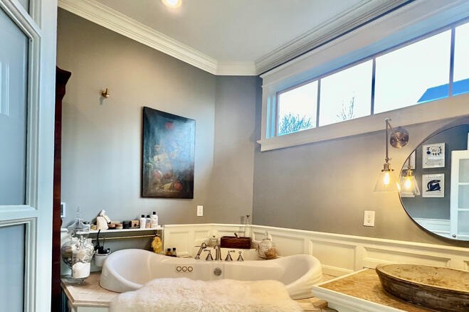 Remodeled bathroom with soaking tub, round mirror and clerestory windows by Luna Park Construction