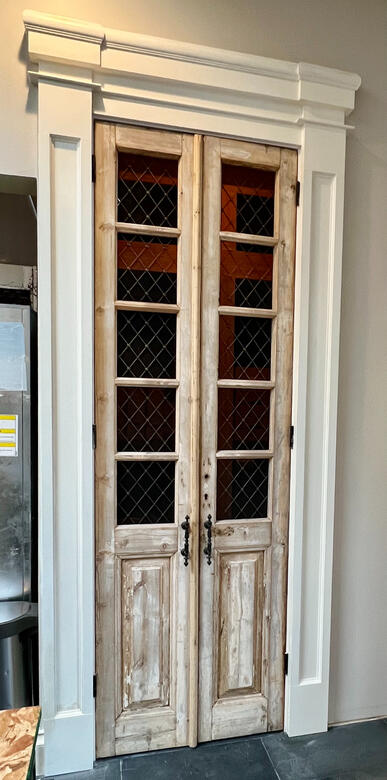 Tall antique glass-panel doors installed in a custom frame