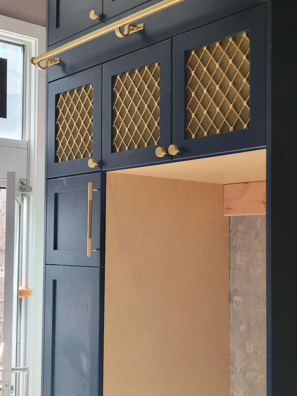 Custom navy cabinetry with brass mesh door inserts