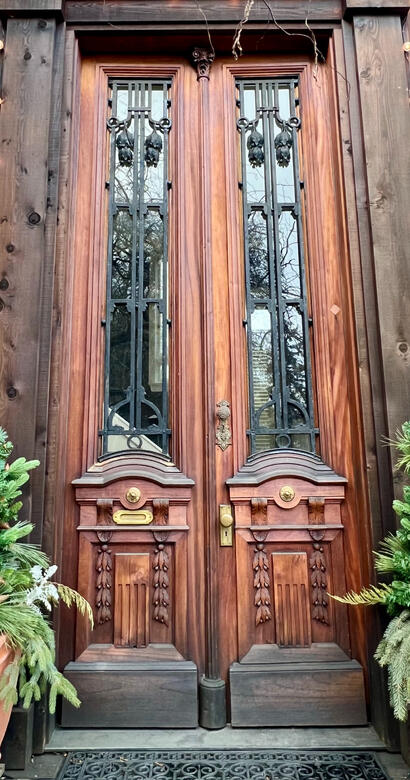 Carved wood double entry doors with wrought-iron glass panels