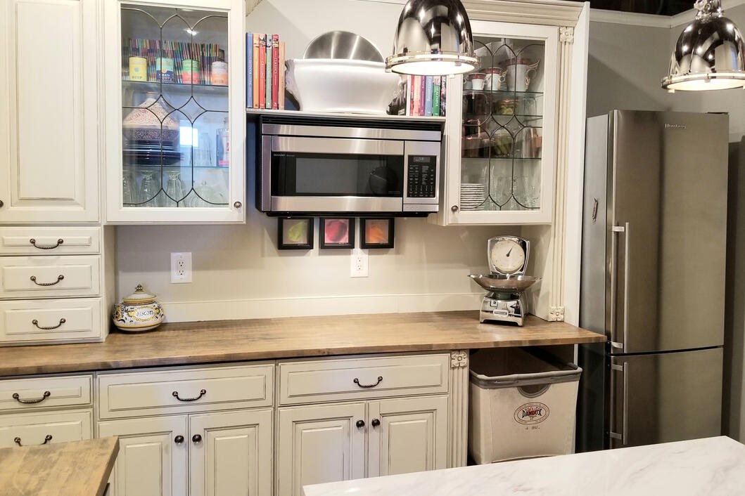 Remodeled kitchen with white cabinetry, glass uppers and butcher-block counters by Luna Park Construction
